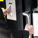 Man pressing an access control keypad to open an office door.