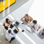 A group of workers in a conference room next to a digital signage display. 