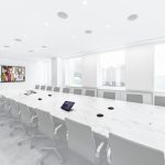A large conference room with two displays, a long table, and in-ceiling speakers.