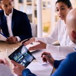 Four people talking in a small conference room.