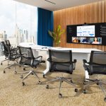 A videoconference room with a large display and a view of a city skyline.